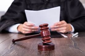 judge holding paper with gavel in front on desk